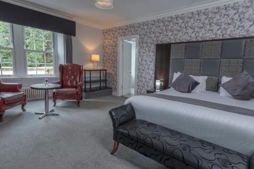a bedroom with a bed and a chair and a table at Buchanan Arms Hotel & Leisure, Sure Hotel Collection in Drymen