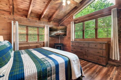 a bedroom in a log cabin with a bed and windows at Eagles Perch Pool Cabin in Rocky Grove