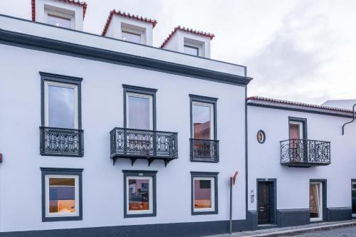 a white house with black balconies on a street at Santa Clara 1828 in Ponta Delgada
