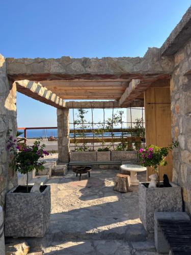 a stone pergola with a bench and a table at Mahakala Center in Petrovac na Moru