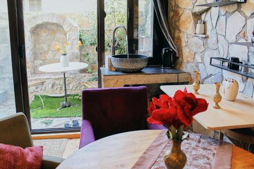 a table with a vase with red flowers on it at Mahakala Center in Petrovac na Moru