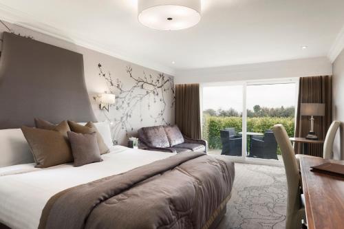 a bedroom with a large bed and a desk and a window at Park Hall Hotel and Spa Wolverhampton in Wolverhampton