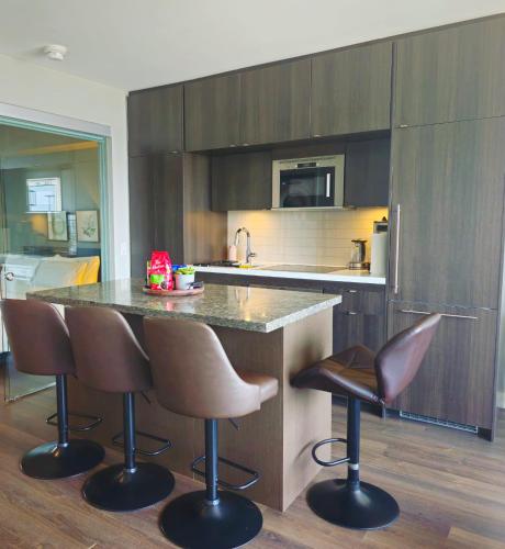 a kitchen with a counter and two bar stools at Yorkville's Premier 2-Bedroom, 2-Bath Suite in Toronto