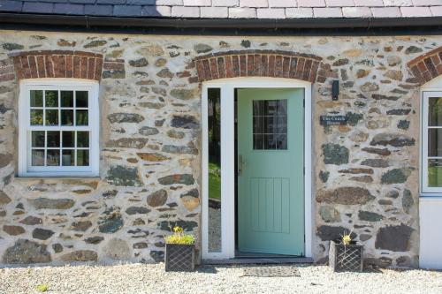 a stone house with a green door and two windows at Coach House in Holyhead
