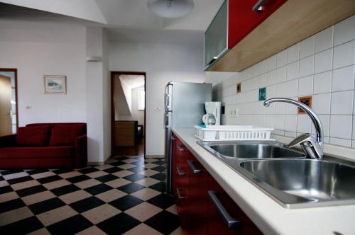 eine Küche mit einer Spüle aus Edelstahl und einem karierten Boden in der Unterkunft Apartments Ida Cres in Cres