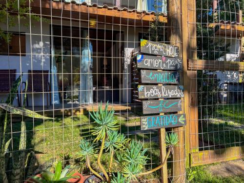 a bunch of signs in front of a building with plants at Amorada do Rosa - 350m do Centrinho do Rosa in Praia do Rosa