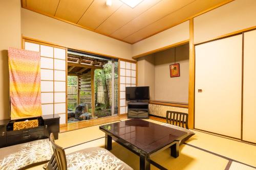 a living room with a coffee table and a tv at Yoshiike Ryokan in Hakone