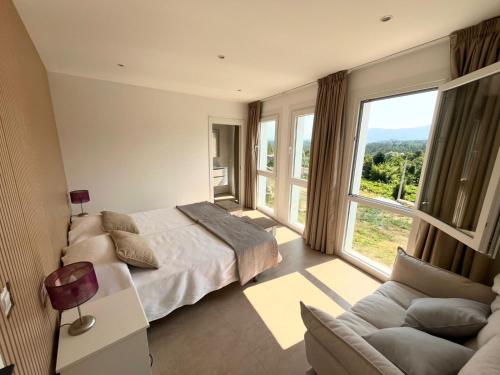 a bedroom with a bed and a couch and a large window at Casa Rural Abreu Do Louro in Arbo