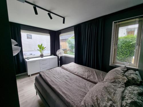 une chambre avec un lit, un bureau et des fenêtres dans l'établissement Spacious and central apartment with a private garden, Free parking and Free EV recharging, à Stavanger