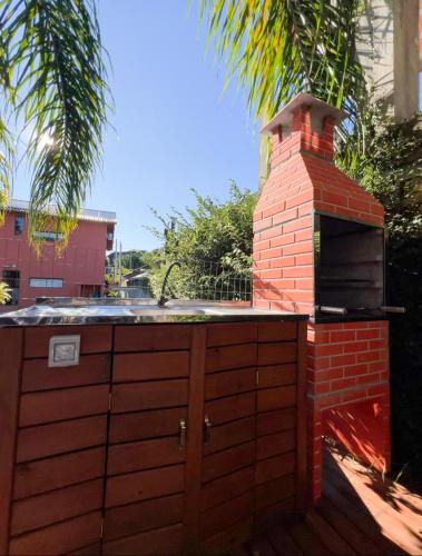 a outdoor kitchen with a brick oven and a sink at Amorada do Rosa - 350m do Centrinho do Rosa in Praia do Rosa