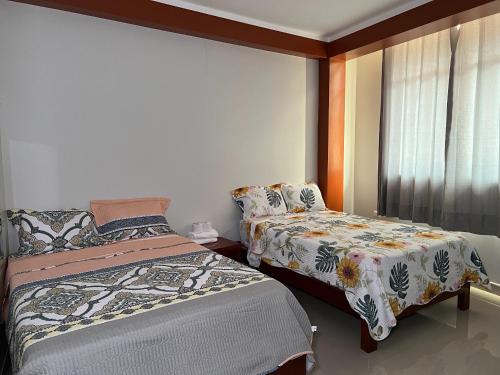a bedroom with two beds and a window at Hostal El Eucalipto Medicinal in Tingo María