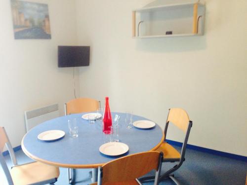 une table bleue avec des chaises et un vase rouge sur elle dans l'établissement La Caillebotière, à La Barre-de-Monts