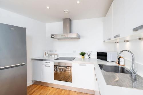 a white kitchen with a sink and a microwave at Stylish 2BR Apartment near Sheffield City Centre in Sheffield