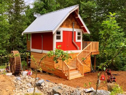 a tiny house with a red door and a deck at Large Estate Venue 2 hot tubs 2 treehouses in Snohomish