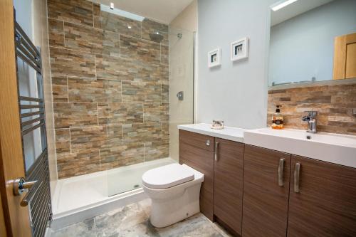 a bathroom with a toilet and a shower and a sink at Gamekeepers Cottage in Holyhead