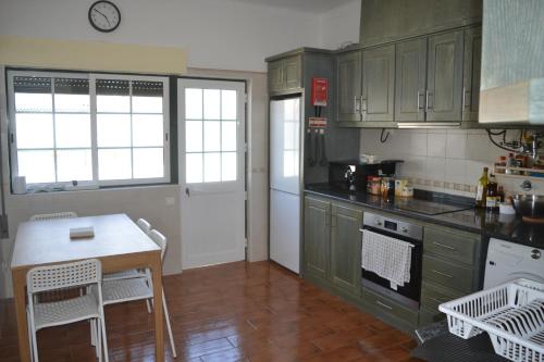 a kitchen with green cabinets and a table in it at OPA Hostel Milfontes in Vila Nova de Milfontes