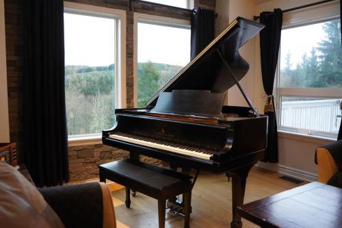 a black piano in a living room with windows at Mountain View Estate Forest Hot Tub Full Arcade in Snohomish