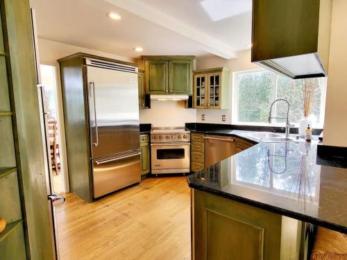 a kitchen with a stainless steel refrigerator and wooden floors at Mountain View Estate Forest Hot Tub Full Arcade in Snohomish