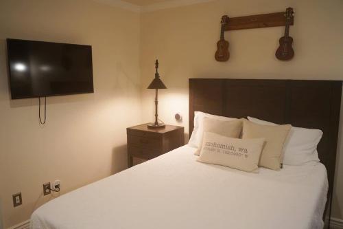 a bedroom with a white bed with a television on the wall at Mountain View Estate Forest Hot Tub Full Arcade in Snohomish