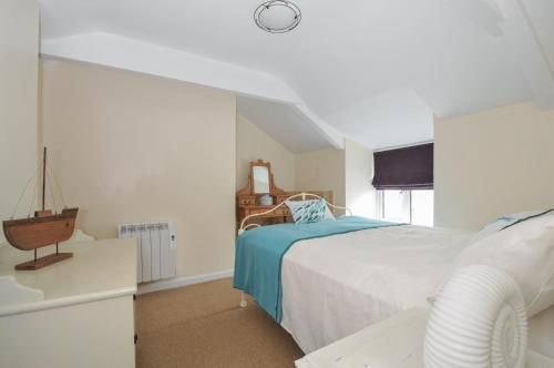 een witte slaapkamer met een bed en een raam bij 2 Porthilly Cottages in Wadebridge