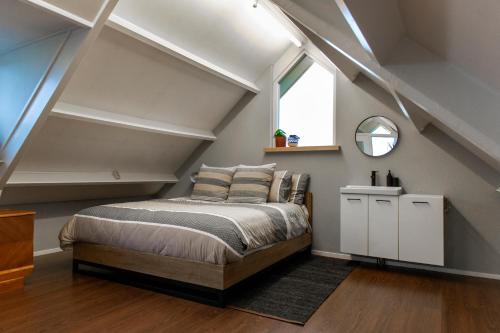 a bedroom with a bed in a loft with a window at City & Nature-Amsterdam NextDoor Free parking 8 person 2 kitchens in Landsmeer