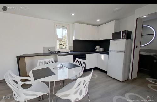 une cuisine avec une table, des chaises et un réfrigérateur dans l'établissement Maison individuelle Aytré plage terrain clos 280m2 très calme, à Aytré