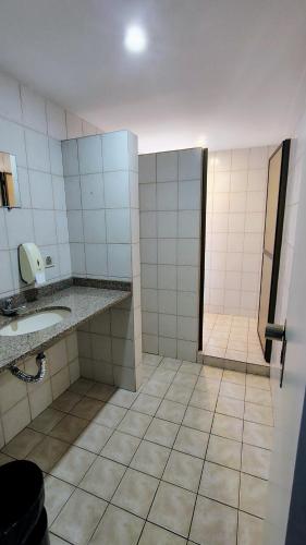 a bathroom with a sink and a stall with a mirror at Extração de Hotel com ótimo custo benefício in Curitiba