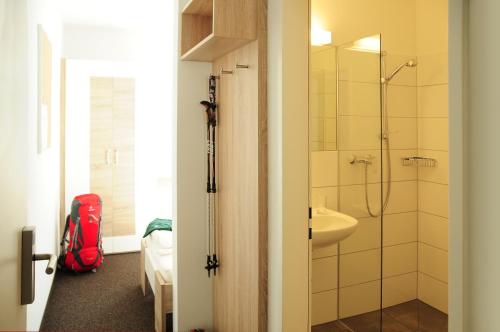 a bathroom with a walk in shower and a red backpack at Haus Gaues in Dalaas