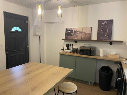 a kitchen with a wooden table and a counter with a microwave at House in forest proche GR and circuit in Saint-Mars-la-Brière