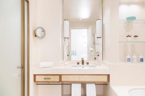 a white bathroom with a sink and a mirror at Hotel La Palma, Oetker Hotels in Capri