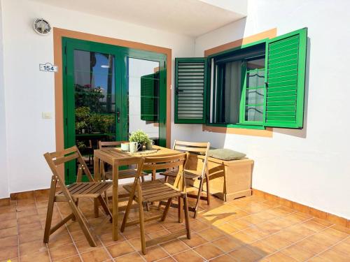 a dining room with green shutters and a table and chairs at El sueño de mi vida in Caleta De Fuste