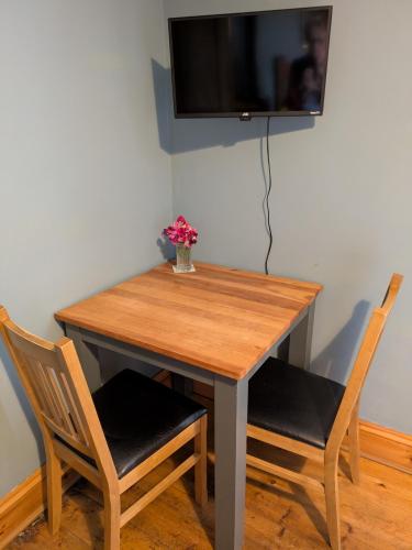 a wooden table with two chairs and a television on a wall at The Manse featuring the Daisy Camrose in Haverfordwest