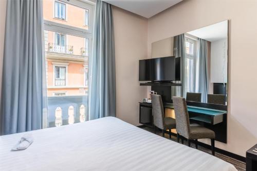 a hotel room with a bed and a desk and a window at Best Western Plus Hotel Universo in Rome