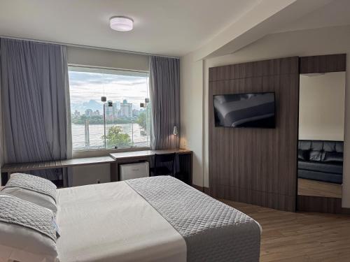 a hotel room with a bed and a television at Hotel Valerim Itajaí / Navegantes in Itajaí