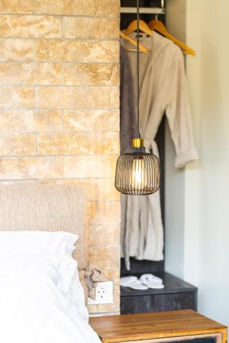 a lamp hanging from a brick wall next to a bed at Tripiti Cozy Flat in Damnoni
