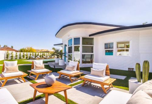 a patio with chairs and tables in front of a house at White Pearl - Pool - Spa - Mountain Views in Palm Springs