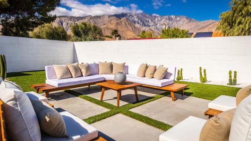 a patio with white couches and a table and chairs at White Pearl - Pool - Spa - Mountain Views in Palm Springs