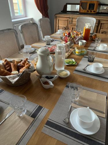 a wooden table with a table with bread and dishes on it at La Maison du Cèdre in Bénévent-lʼAbbaye