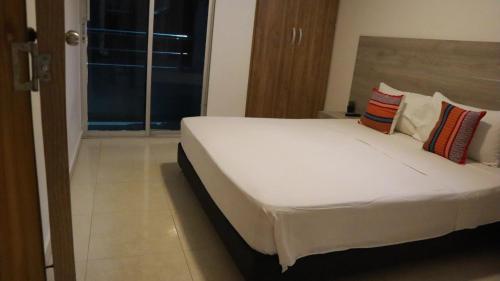 a bedroom with a bed with white sheets and pillows at D-rio Apto in Ríohacha