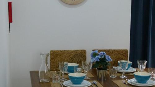 a wooden table with blue bowls and glasses on it at Watching Azores Apartment in Ponta Delgada