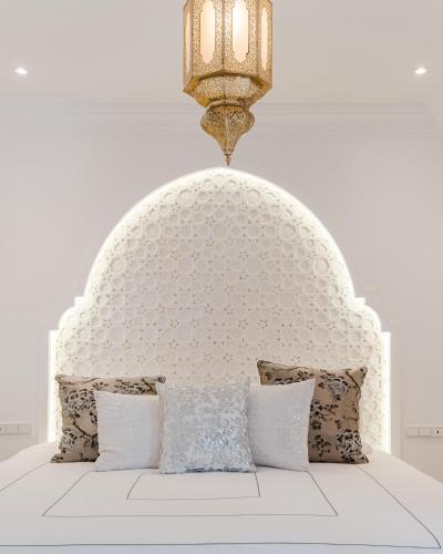 a bed with a white headboard and a chandelier at Free People Riad and Spa in Marrakesh