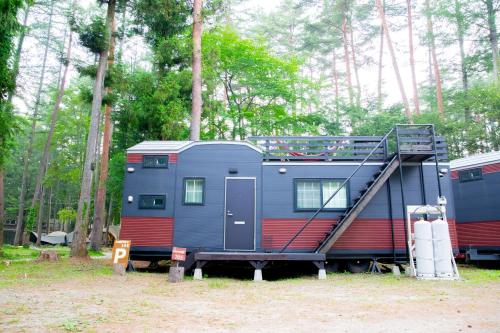 a blue and red rv parked in the woods at 森と湖の楽園ＷorkshopＣampＲesort in Fujikawaguchiko