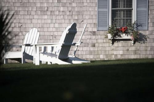 two chairs and a table in front of a house at Wequassett Resort and Golf Club in East Harwich