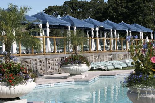 a swimming pool with blue umbrellas and flowers at Wequassett Resort and Golf Club in East Harwich