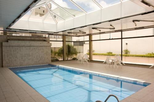 an indoor swimming pool with chairs and a building at Biazi Plaza Hotel in Bauru