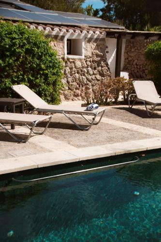 a swimming pool with two lounge chairs and a table at Hotel Rural Biniarroca - Adults Only in Sant Lluis