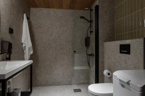 a bathroom with a shower and a toilet and a sink at H28 - Hotel, Apartments and Suites by UHANDA in Tampere