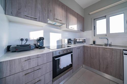 a kitchen with wooden cabinets and a stove top oven at Majestic Sunset Salt Lake Views 300m From Beach in Larnaka