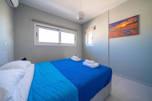 a bedroom with a blue bed with two towels on it at Majestic Sunset Salt Lake Views 300m From Beach in Larnaka