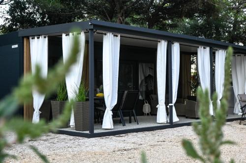 a black and white gazebo with white curtains at Mobile home Periska, Pakoštane in Pakoštane